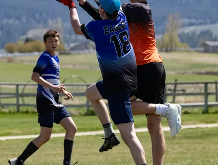 Player leaping to catch the disc over a defender with mountains in the background